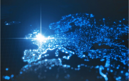 A glowing blue map of Europe with illuminated dots representing major cities. A bright light shines over Western Europe, highlighting the area against a dark background.