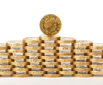 A pyramid of stacked British one-pound coins with one coin standing upright on top, showcasing the engraved design. The coins' edges are visible, displaying their intricate details.