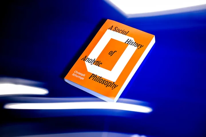 A book titled "A Social History of Analytic Philosophy" by Christoph Schuringa rests on a vivid blue surface, with white streaks of light surrounding it. The book cover is orange with bold black and white text.