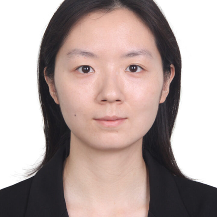 A woman with straight, dark hair and fair skin is facing the camera. She is wearing a black blazer and has a neutral expression against a plain white background.